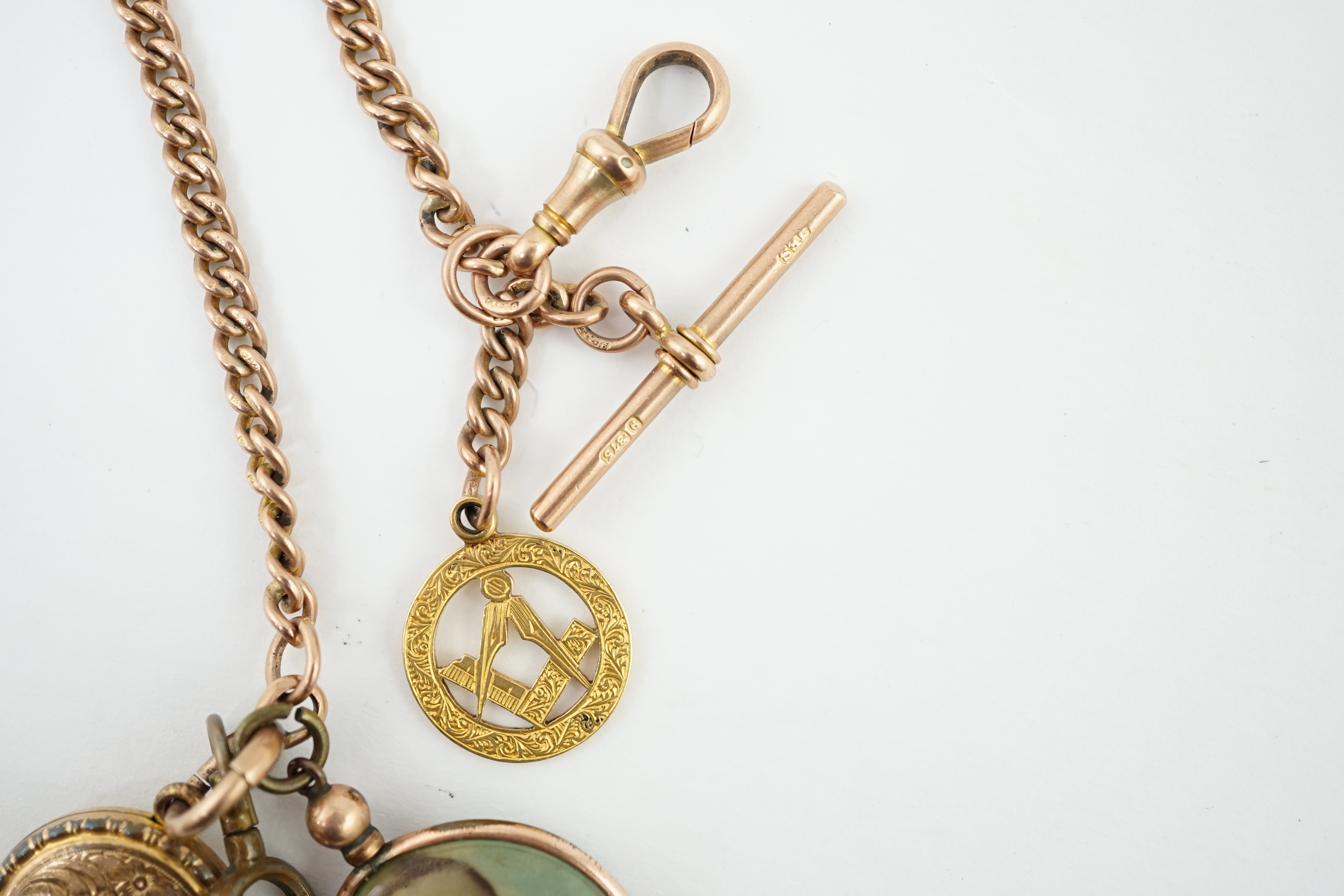 An Edwardian 9ct gold curb link albert, hung with a 9ct gold Masonic charm, locket and a double sided portrait pendant